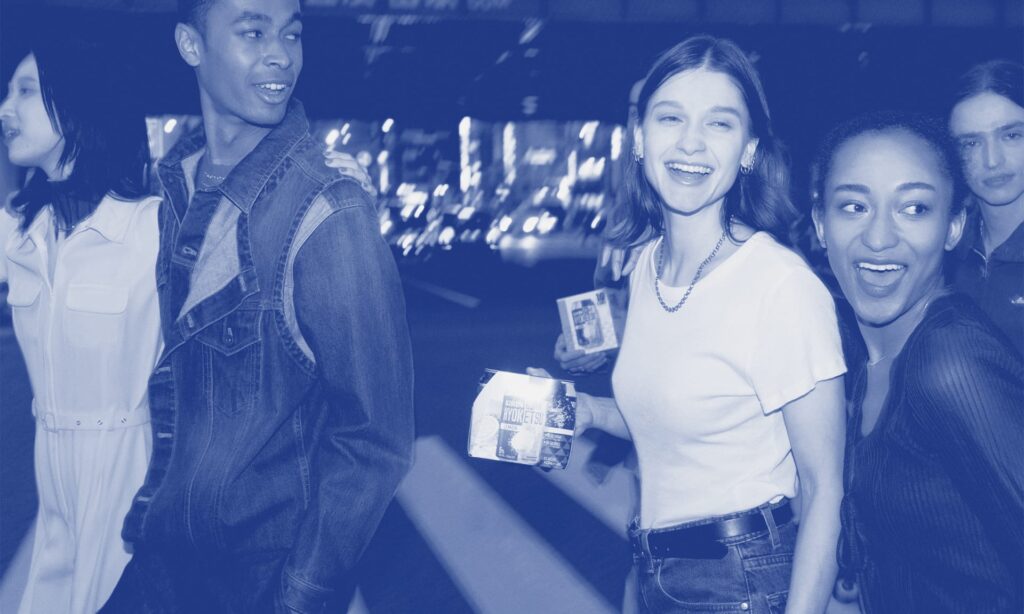 A group of cool looking friends smiling and laughing as the enjoy cans of Kirin Hyoketsu as they walk around a Japanese looking city-scape